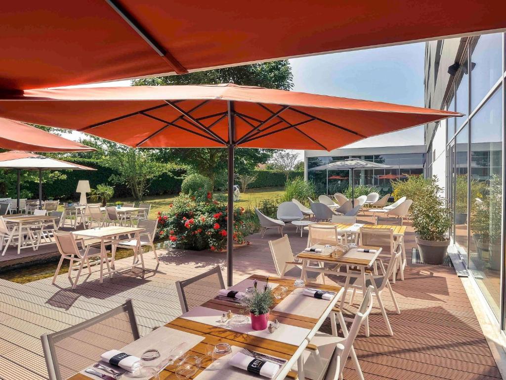 a patio with tables and chairs with umbrellas at Mercure Lyon Genas Eurexpo in Genas