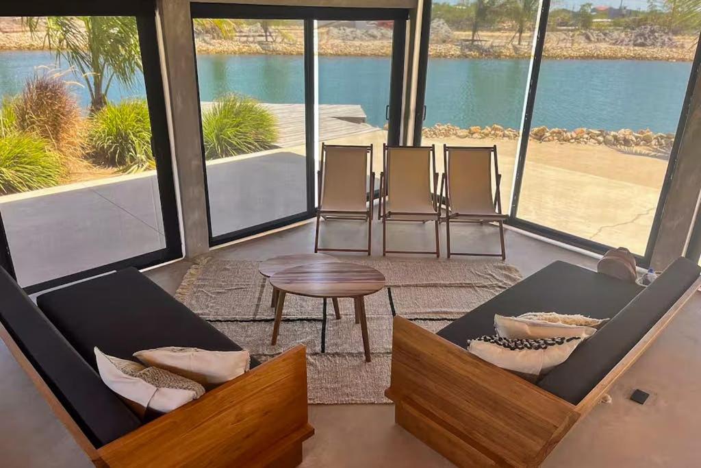 a living room with chairs and a table and a large window at Seabird - Villa 10 in Placencia