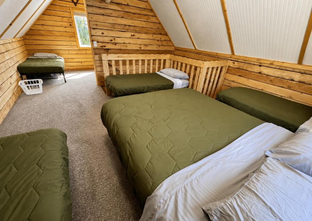 a room with three beds in a log cabin at Sockeye Salmon Sanctuary, Cabin 6 at Lower Kenai Lodge in Kenai