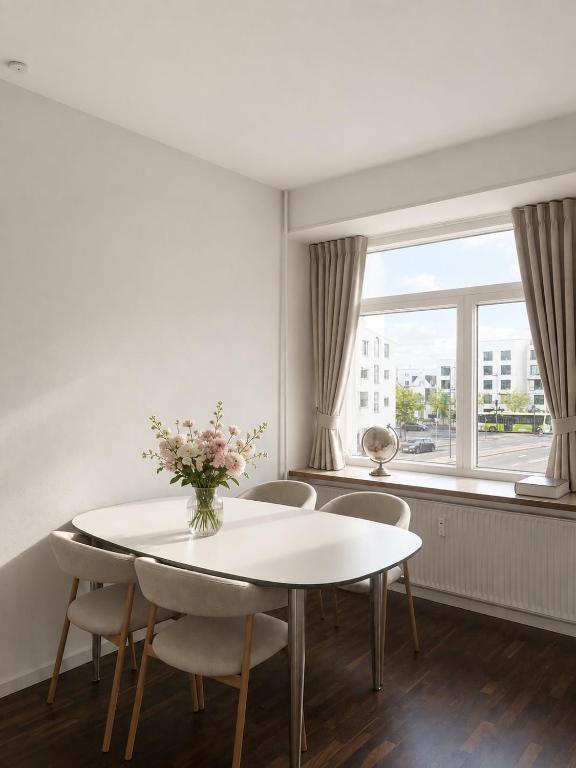 a white dining room with a table and chairs and a window at NØ -Central Apartment Odense C in Odense