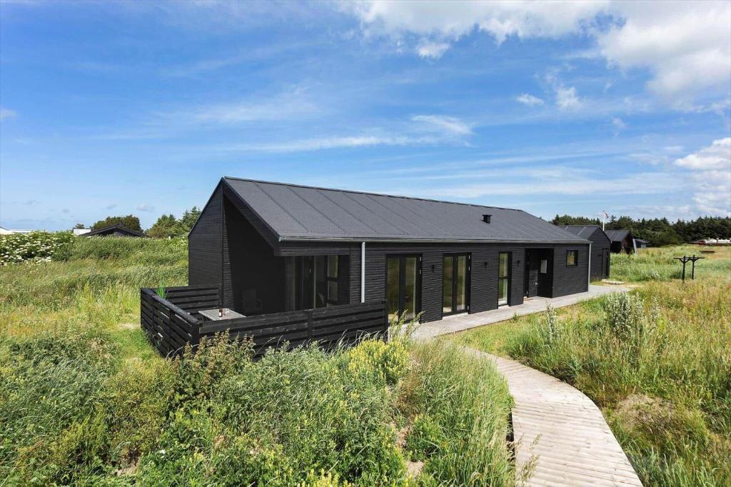 a black house in the middle of a field at TV1737-Bindslev-Mellemklitvej-23 in Tversted