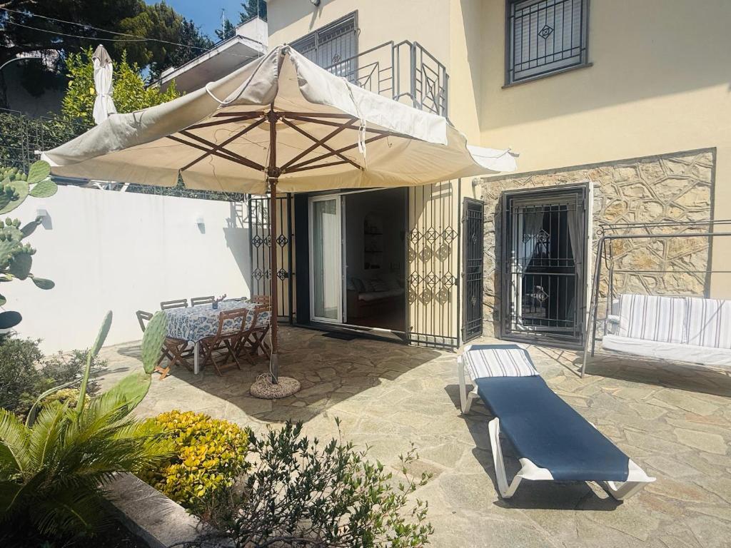 a patio with an umbrella and a bench and a table at Villa Fronte Mare Con Terrazza in Marina di Andora