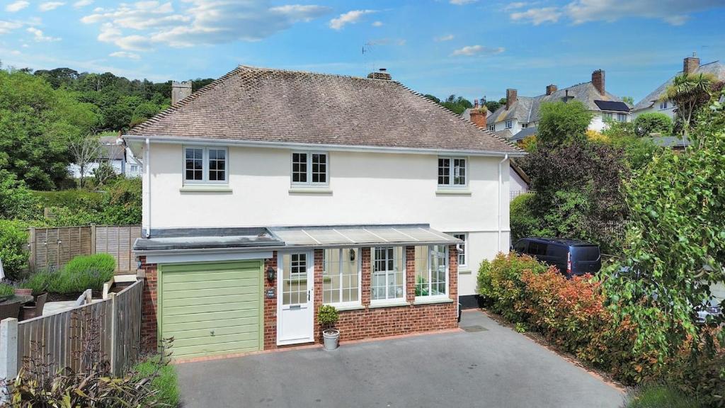 a white house with a green garage at Barn Cottage in Minehead