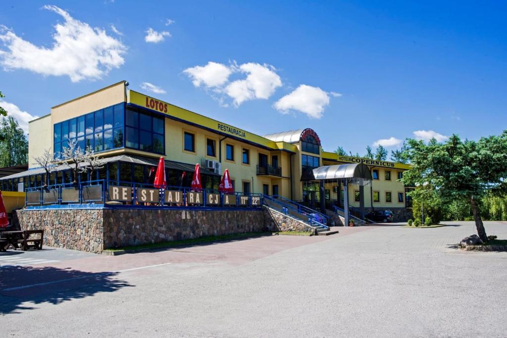 een hotel met vlaggen voor een gebouw bij Hotel Copernicus in Lubawa