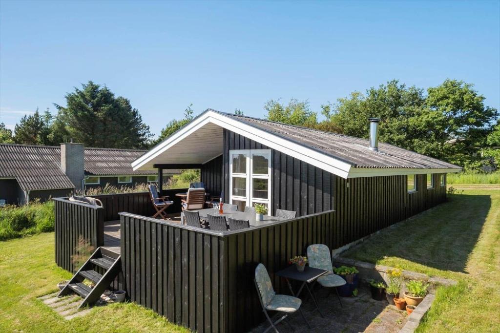 a black tiny house with a deck and chairs at JB507-Fjerritslev-Perikumvej-50 in Slettestrand