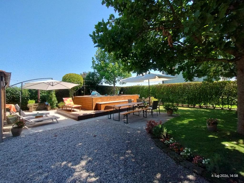 a patio with a bench and tables and an umbrella at Turistica Via Po 7 in Legnago
