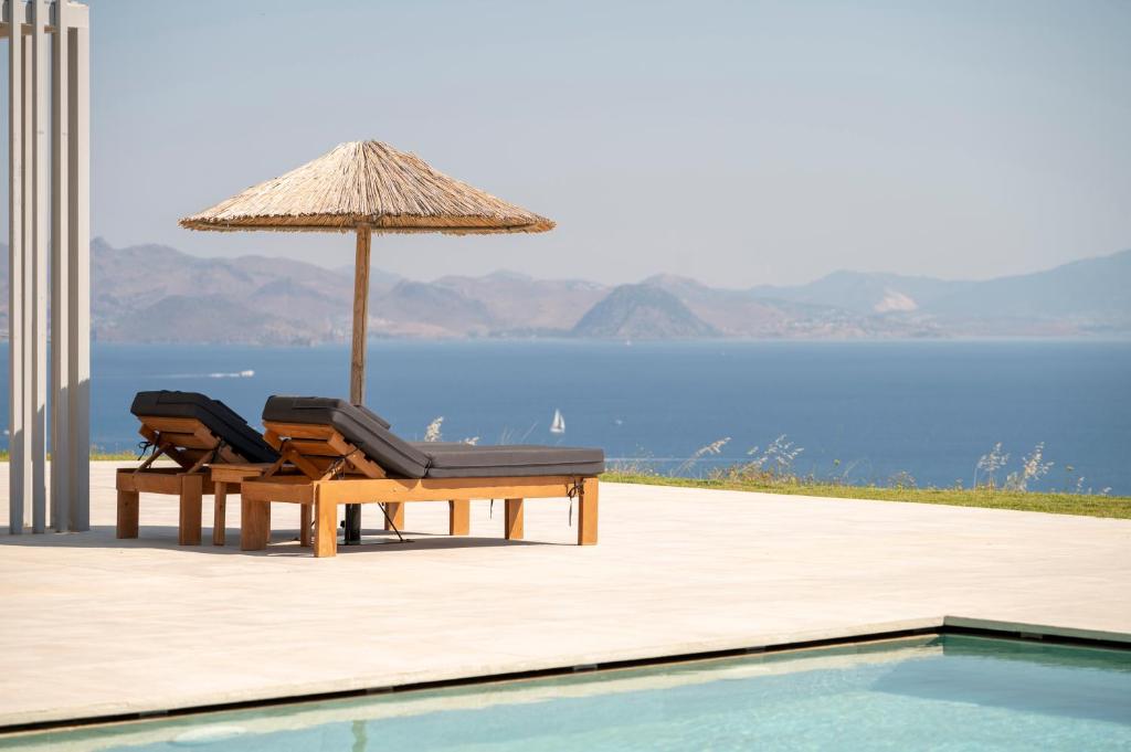 a pair of chairs and an umbrella next to a swimming pool at Thalori villa 2 in Psalidi
