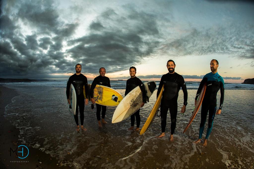 a group of men standing on the beach holding surfboards at El Pez Escorpion in Salinas