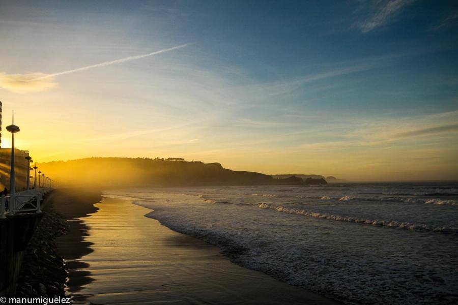 a beach with the sun rising over the ocean at El Pez Escorpion in Salinas