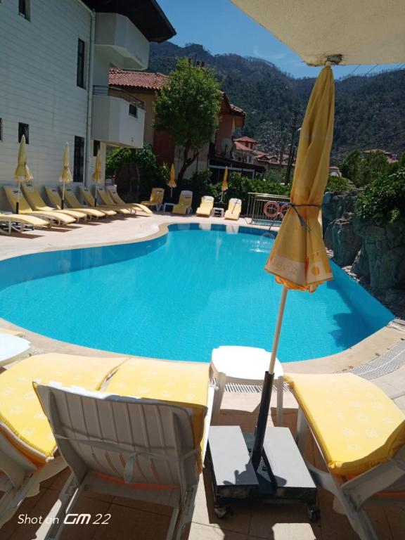 a swimming pool with lounge chairs and an umbrella at ÖZ-AY APART OTEL in Marmaris