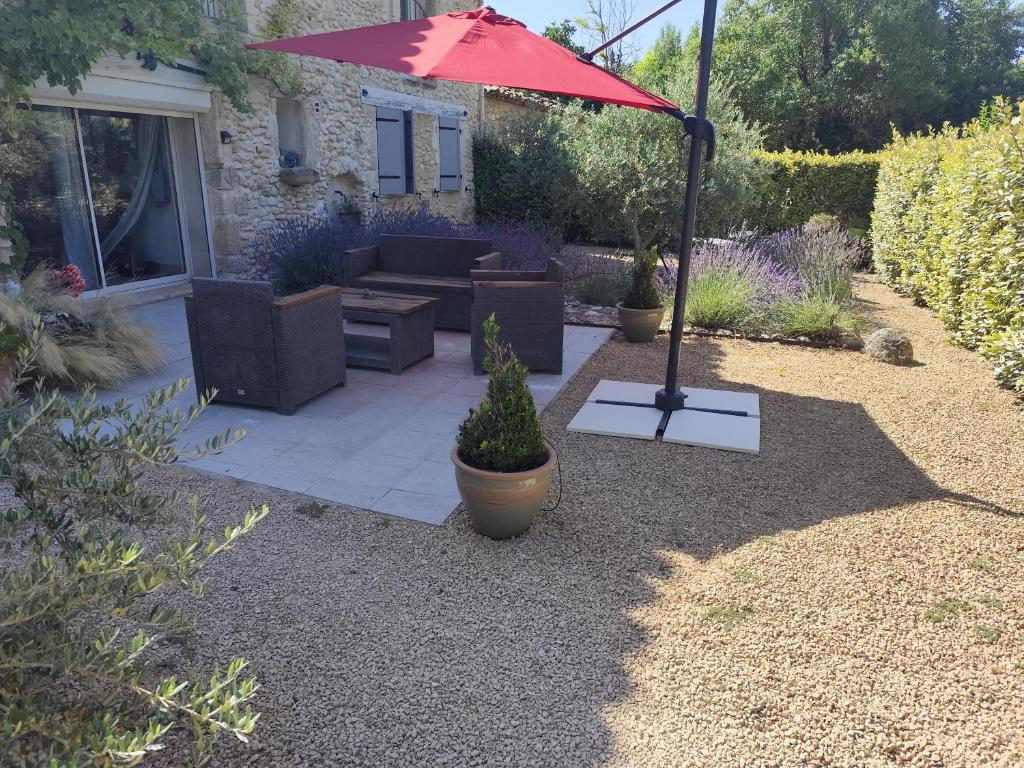 a patio with a red umbrella and a couch at Le Mas du Four a Chaux in Gordes