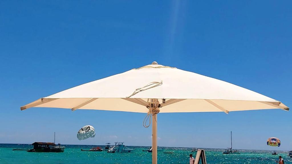 a large white umbrella sitting on the beach at Hotel Beach Pool Punta Cana Vacation in Punta Cana