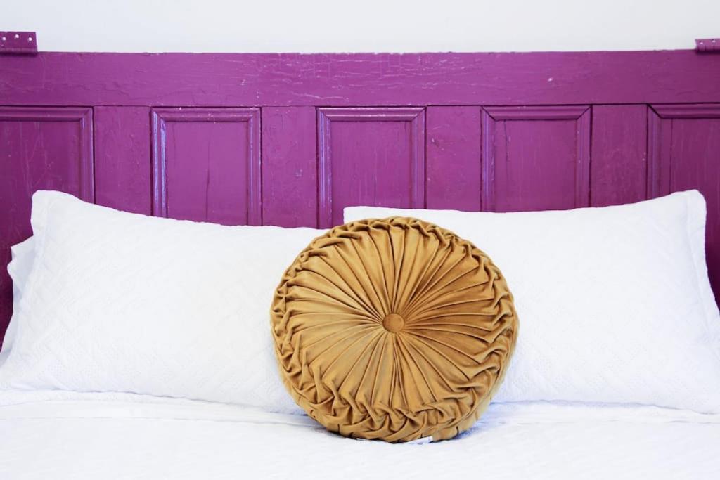 a pillow sitting on a bed with a purple headboard at 4 Guest Suite with Waterfront Views at Fancie's PEC - Suite 2 in Belleville