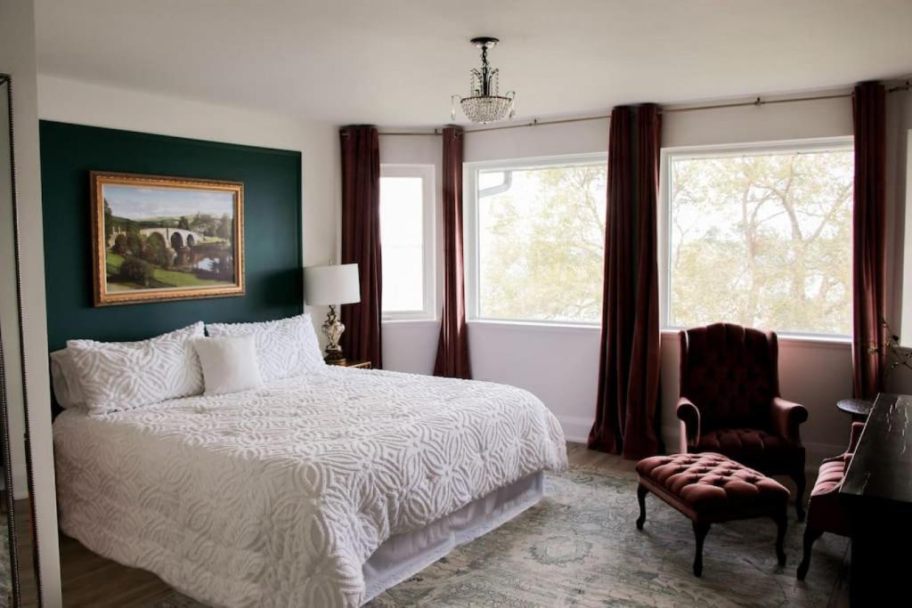 a bedroom with a bed and a chair and windows at Waterfront Boutique Accommodation in PEC - Suite 3 in Belleville