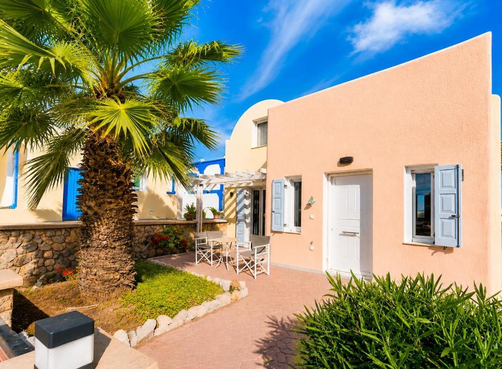 a house with a palm tree in front of it at Roxys sea view Santorini Monolithos in Santorini