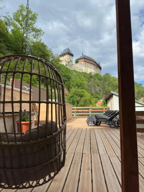 a bird cage on a wooden deck with two castles at Wellness apartment Karlštejn in Karlštejn