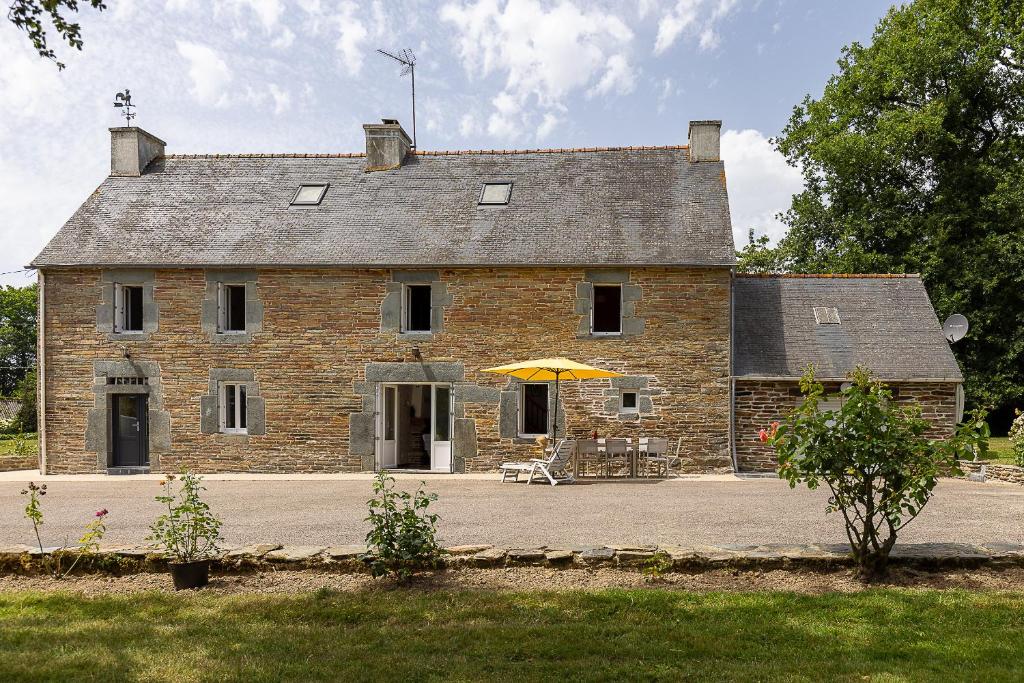 an old brick house with an umbrella in front of it at Ti Coet Salio - Nature & calme près de Guerlédan in Guerlédan