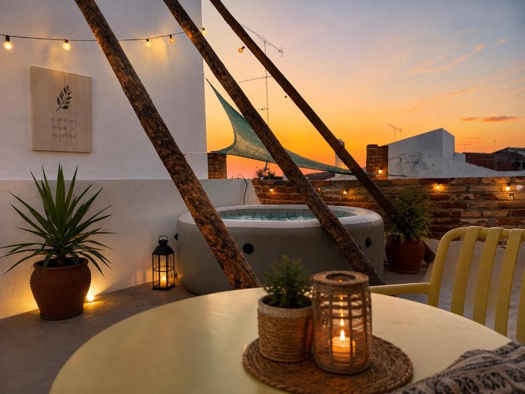 a balcony with a tub and a table and a sunset at Pátio 38 do frade in Aldeia do Mato