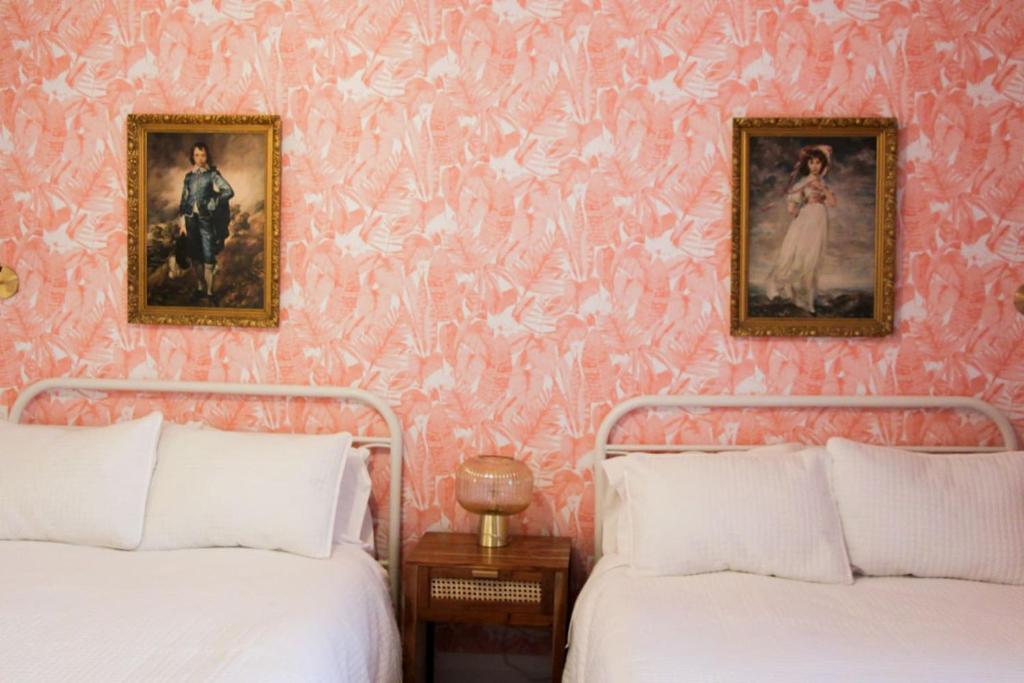 two beds in a bedroom with pink wallpaper at Boutique Accommodation in PEC - Suite 4 in Belleville