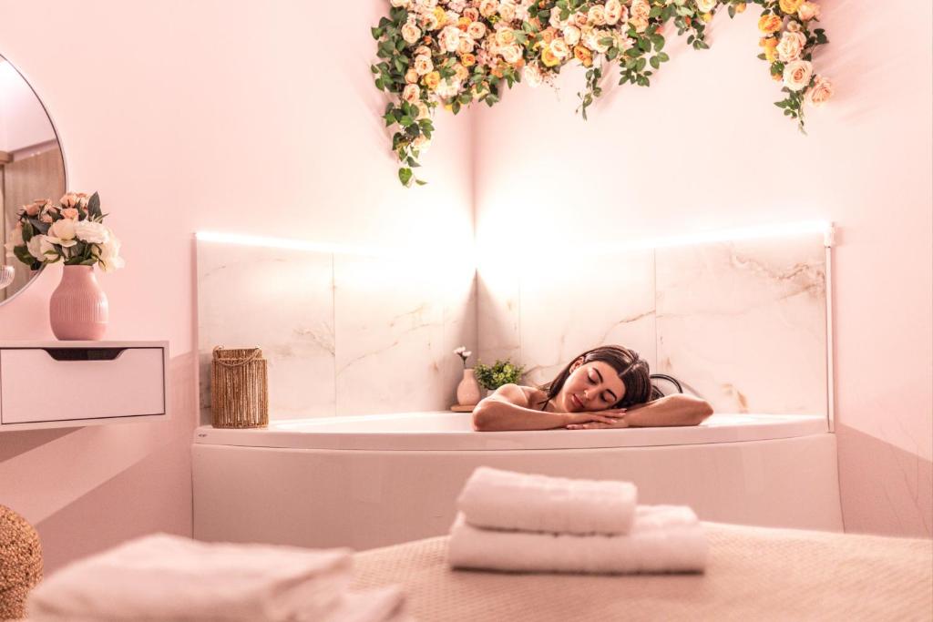 a woman laying in a bath tub with a mirror at Almond Jacuzzi Suites - Private Indoor Jacuzzi - Self Check-In - Free & Easy Street Parking in Thessaloniki