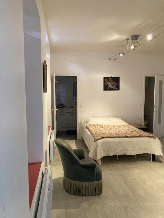 a bedroom with a bed and a green chair at STUDIO hyper centre in Bagnoles de l'Orne
