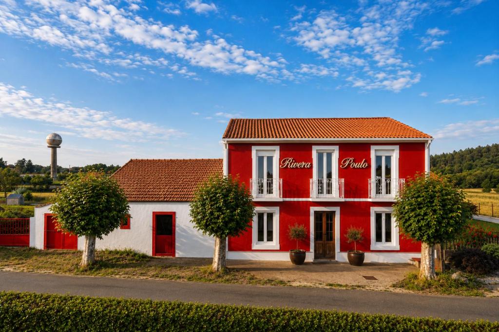 a red and white building with trees and a water tower at Rivera de Poulo in Ordes