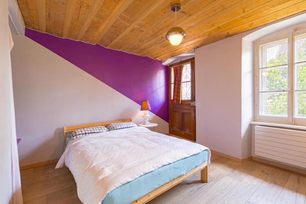 a bedroom with a purple accent wall and a bed at Farm & Chill Guesthouse in Thierrens