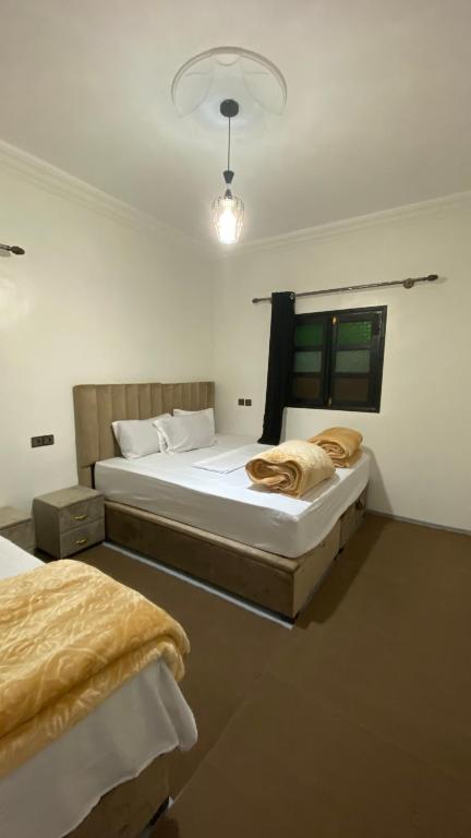 a bedroom with two beds and a light on the wall at Beldi apparemment in Imlil