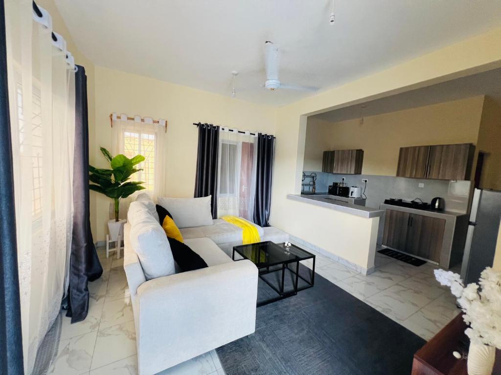 a living room with a white couch and a kitchen at The Wink apartments in Malindi