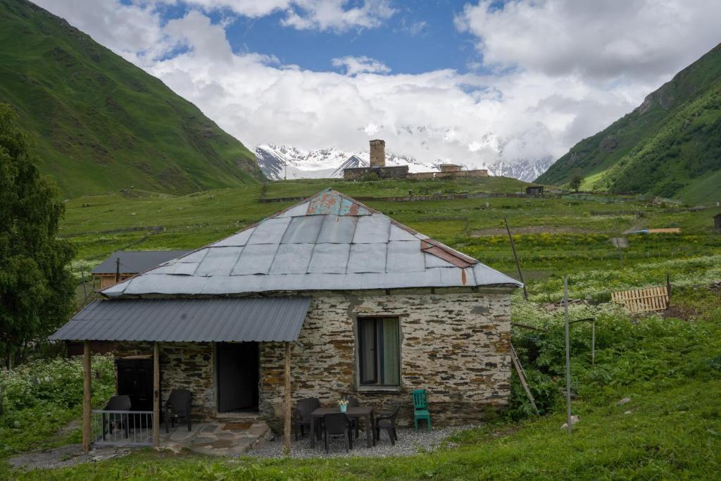 a small stone building in a field with mountains at Koruld Ushguli in Chvibiani