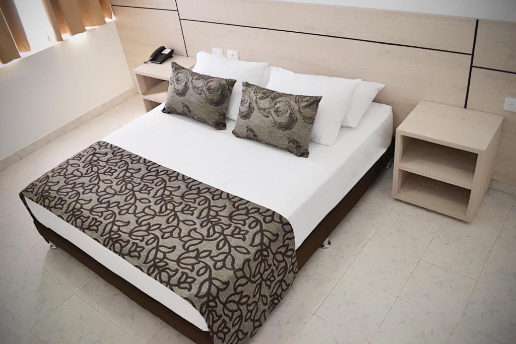 a bedroom with a bed with a black and white comforter at Hotel Kurakatá in Valledupar