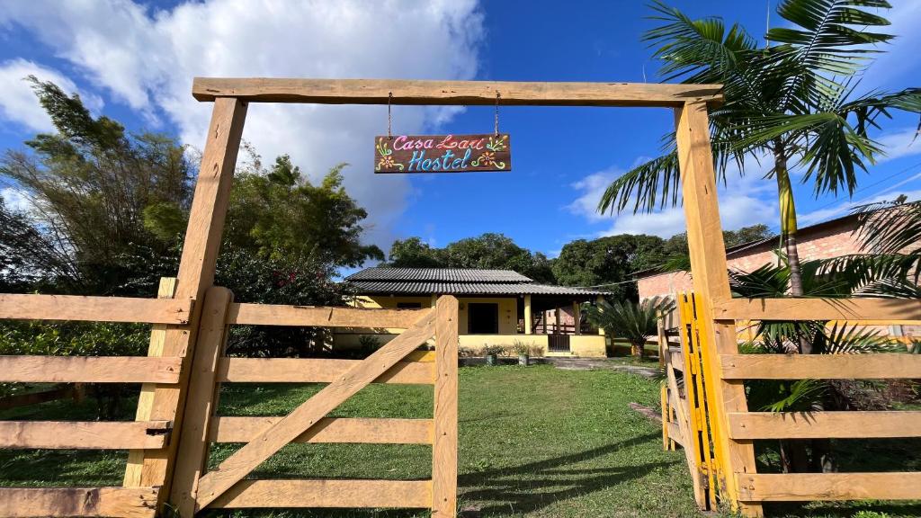 a wooden gate in front of a house with a sign at Casa Lari Hostel in Vila Tepequém