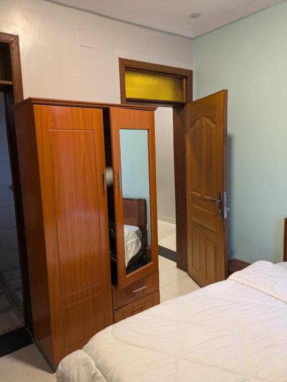 a bedroom with a bed and a wooden cabinet with a mirror at Star real in Kigali