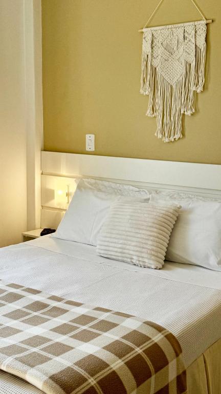 a bedroom with a bed with white sheets and a chandelier at Pousada da Mariinha in São Lourenço