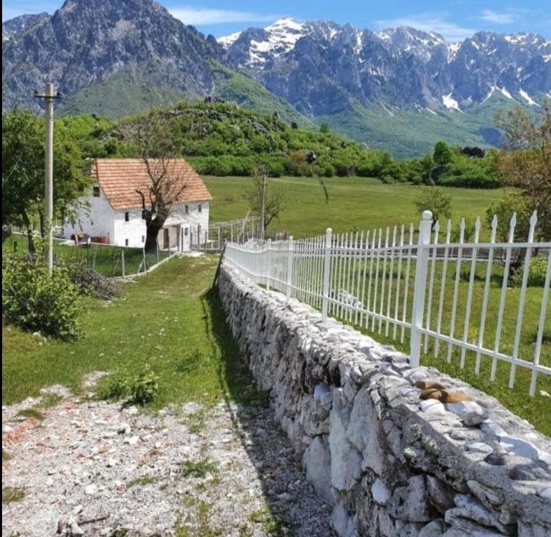 a stone wall with a fence and mountains in the background at Guest House Avdi Kola in Gagu