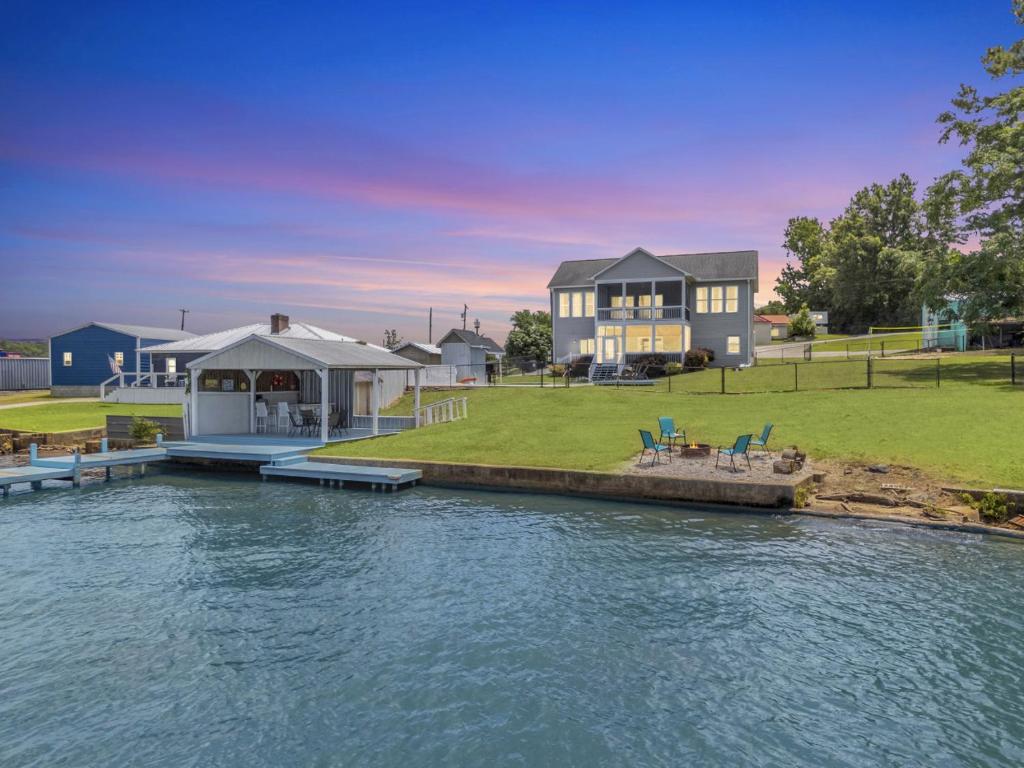 a house with a dock next to a body of water at Lakefront Getaway with Dock, Pool, Sunset Games in Greenwood
