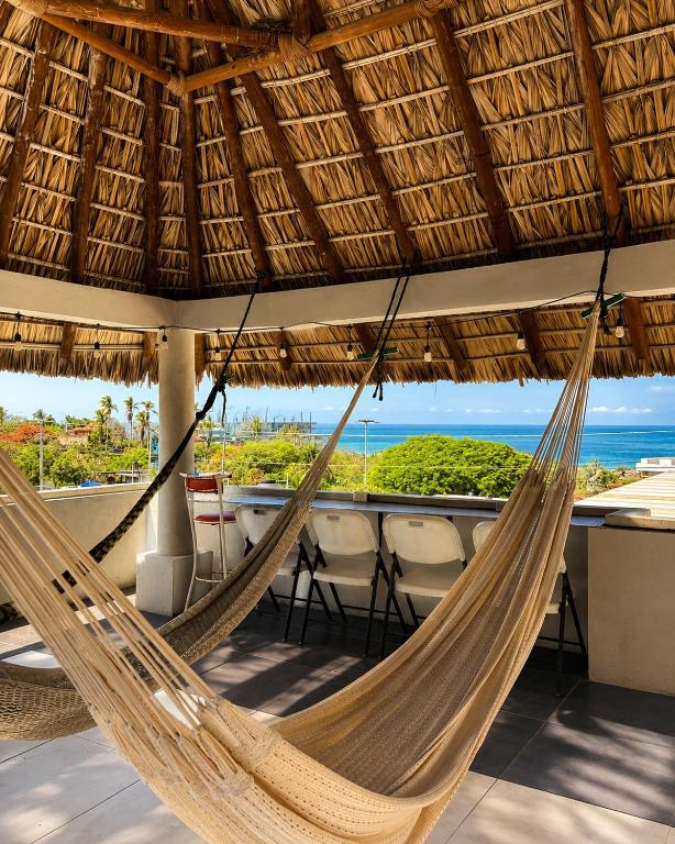 a hammock hanging from a straw umbrella on a beach at Casa Alma de Mar in Brisas de Zicatela
