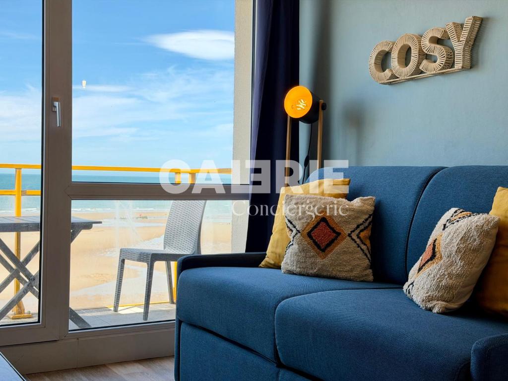 a blue couch in a living room with a balcony at GC - Le Panorama - Front de Mer in Wissant