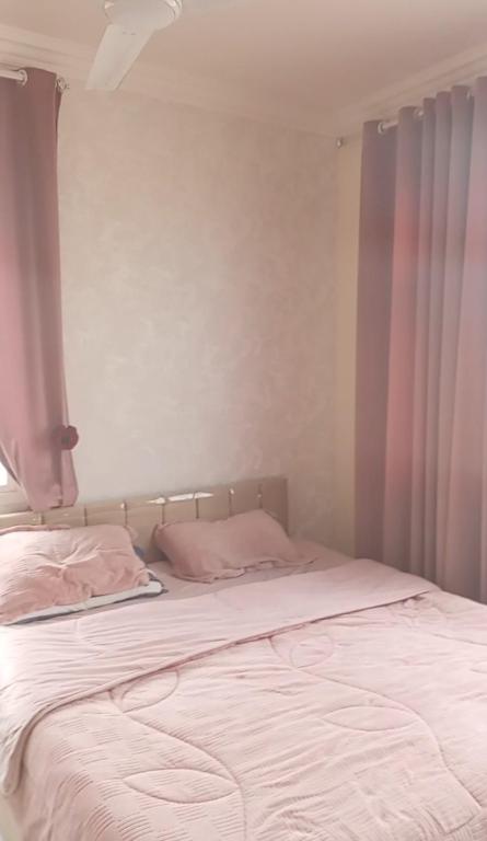 a bed with white sheets and pillows in a bedroom at صلاله الدهاريز الجنوبيه in Daḩārīz
