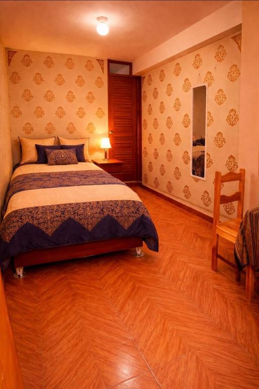 a bedroom with a bed and a wooden floor at Hospedaje Shalom in Pisac