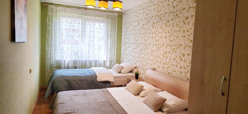 a small room with two beds and a window at Deivido apartamentai Šiauliuose in Šiauliai