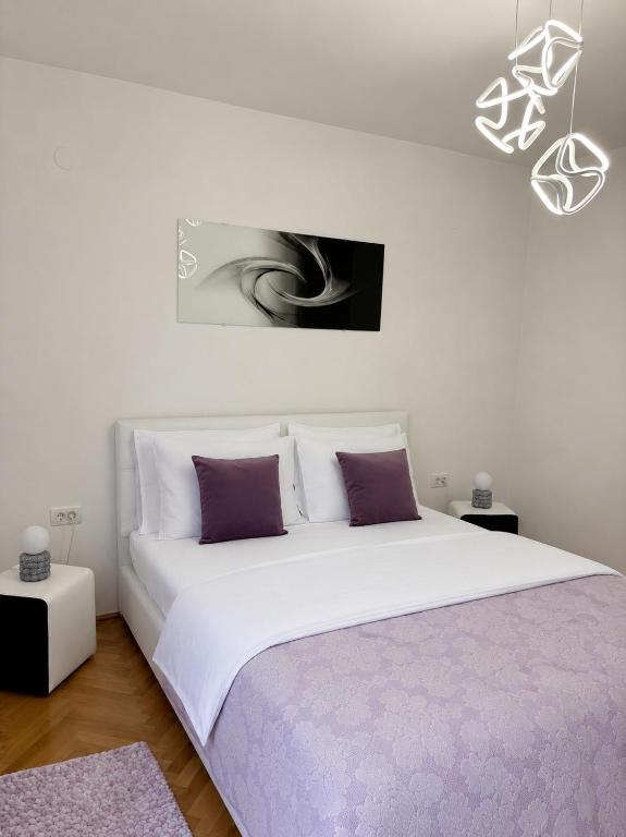 a bedroom with a large white bed with purple pillows at Lux Apartman Casablanca in Plužine