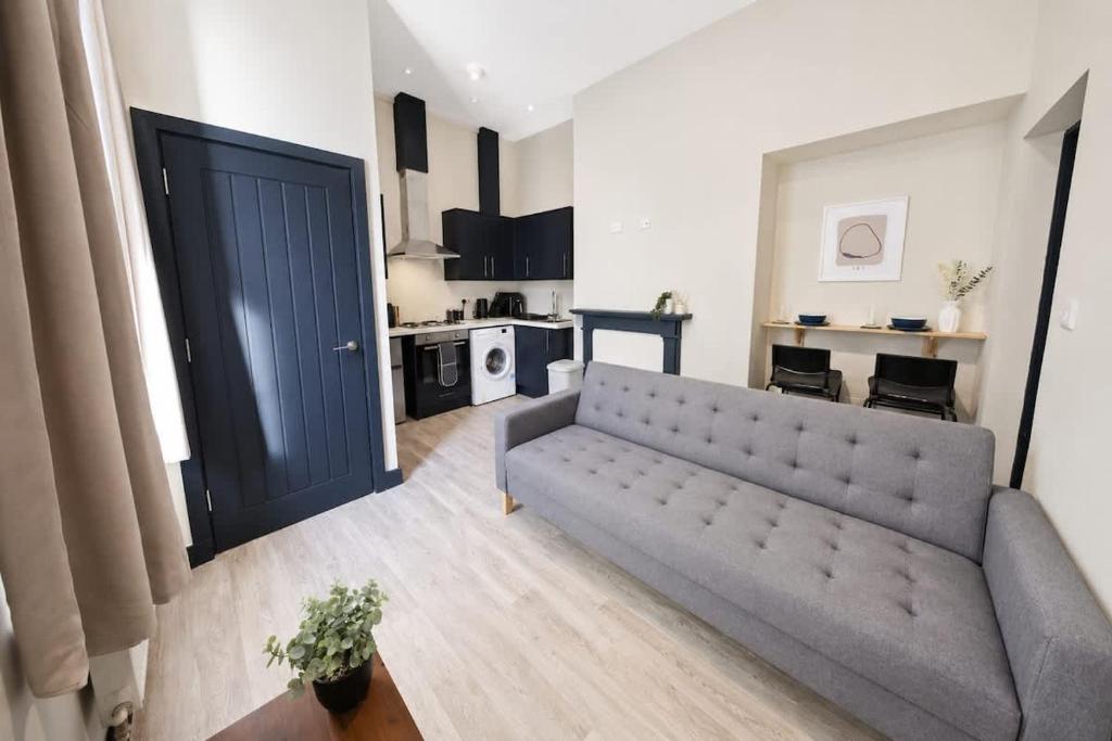 a living room with a couch and a kitchen at Amazing City Centre Apartment in Derby