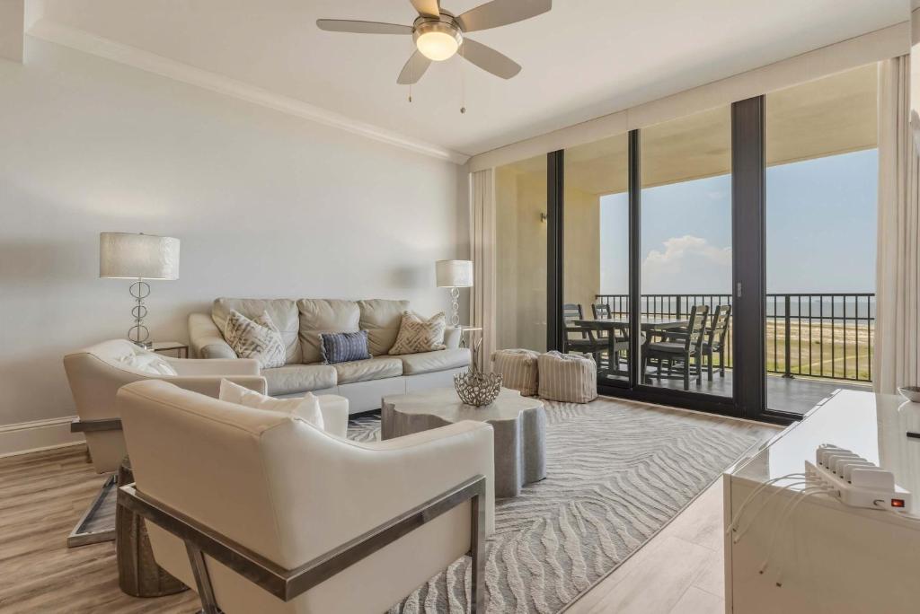 a living room with a couch and a ceiling fan at Luxury GulfFront Penthouse with Resort Amenities in Dauphin Island