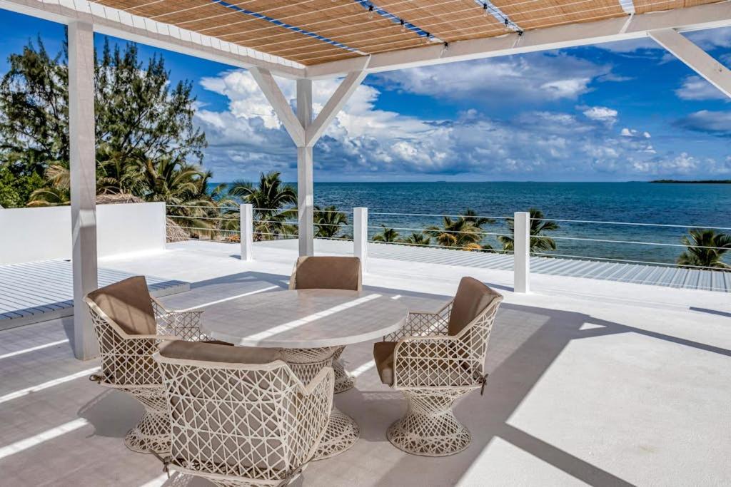a patio with a table and chairs and the ocean at White Sands Beach House in Maya Beach