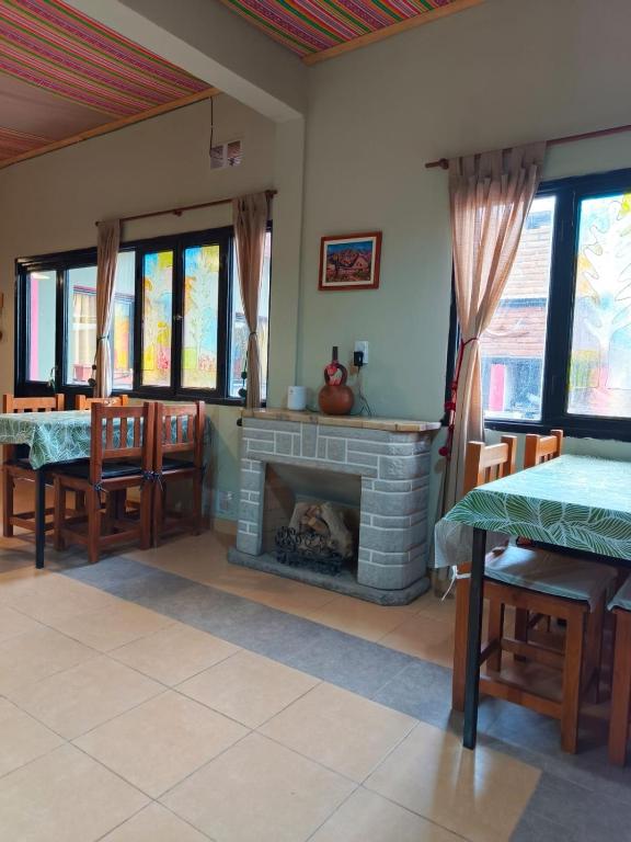 a living room with a fireplace and a table and chairs at Hostel El Alamo in Maimará