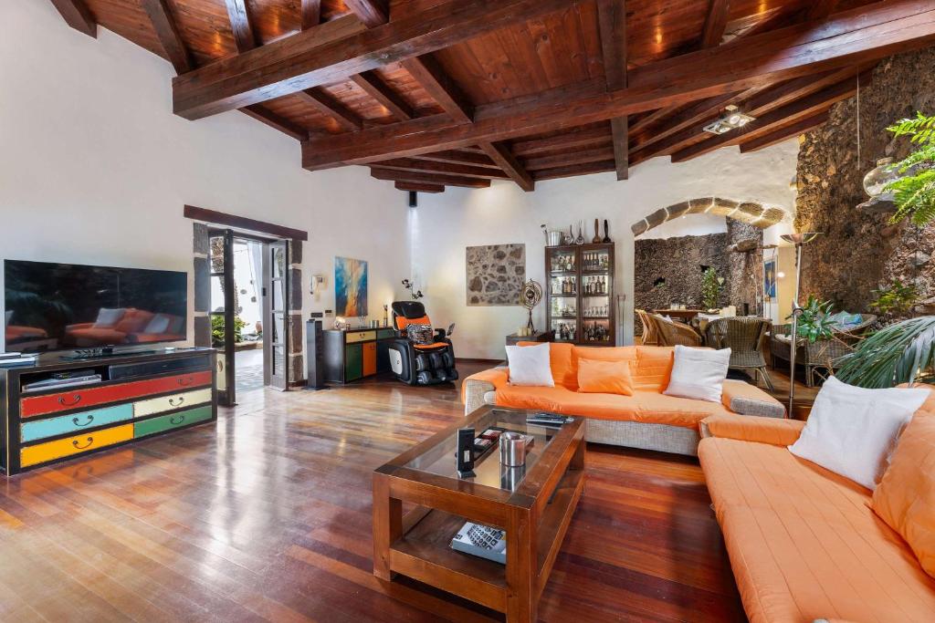 Una sala de estar con sofás naranjas y un televisor. en Villa Muller by Bayside - The Fountain of Silence, en Tías