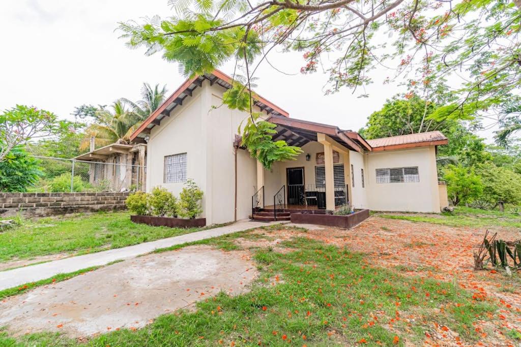a small white house with a yard at Campo Verde House in San Ignacio