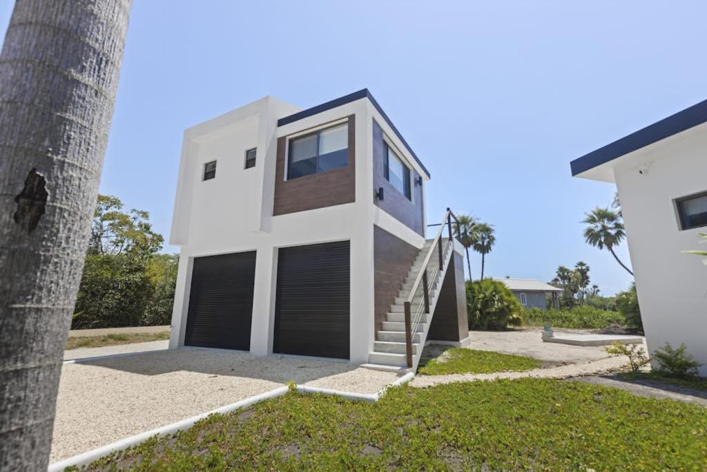 a house with two garage doors next to a palm tree at Beyond the Blue Casita in Placencia