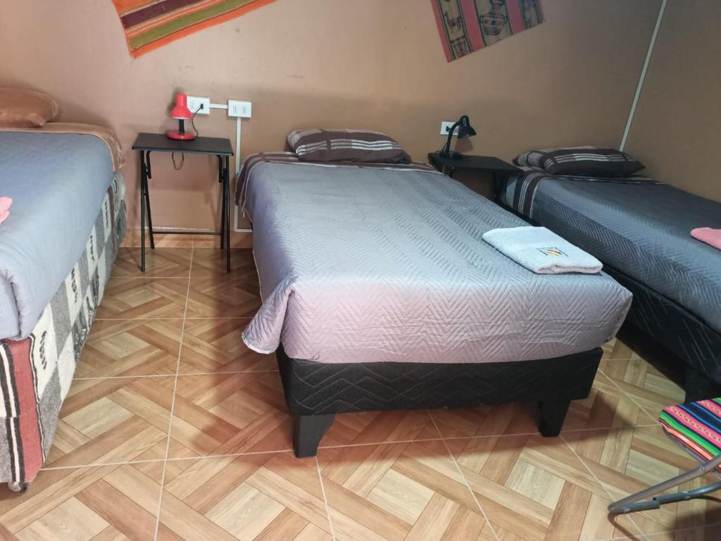 a room with three beds and a wooden floor at CASA HOSTAL LA PASKANA ATACAMEÑa in San Pedro de Atacama